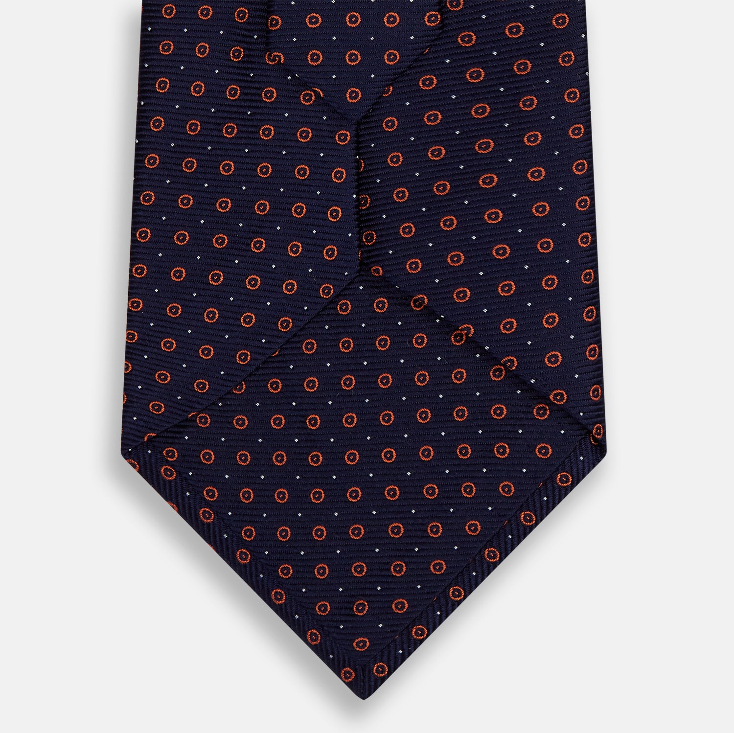 View 3 of product A Navy and Orange Circle Silk Tie by Turnbull & Asser, neatly rolled on a white background.