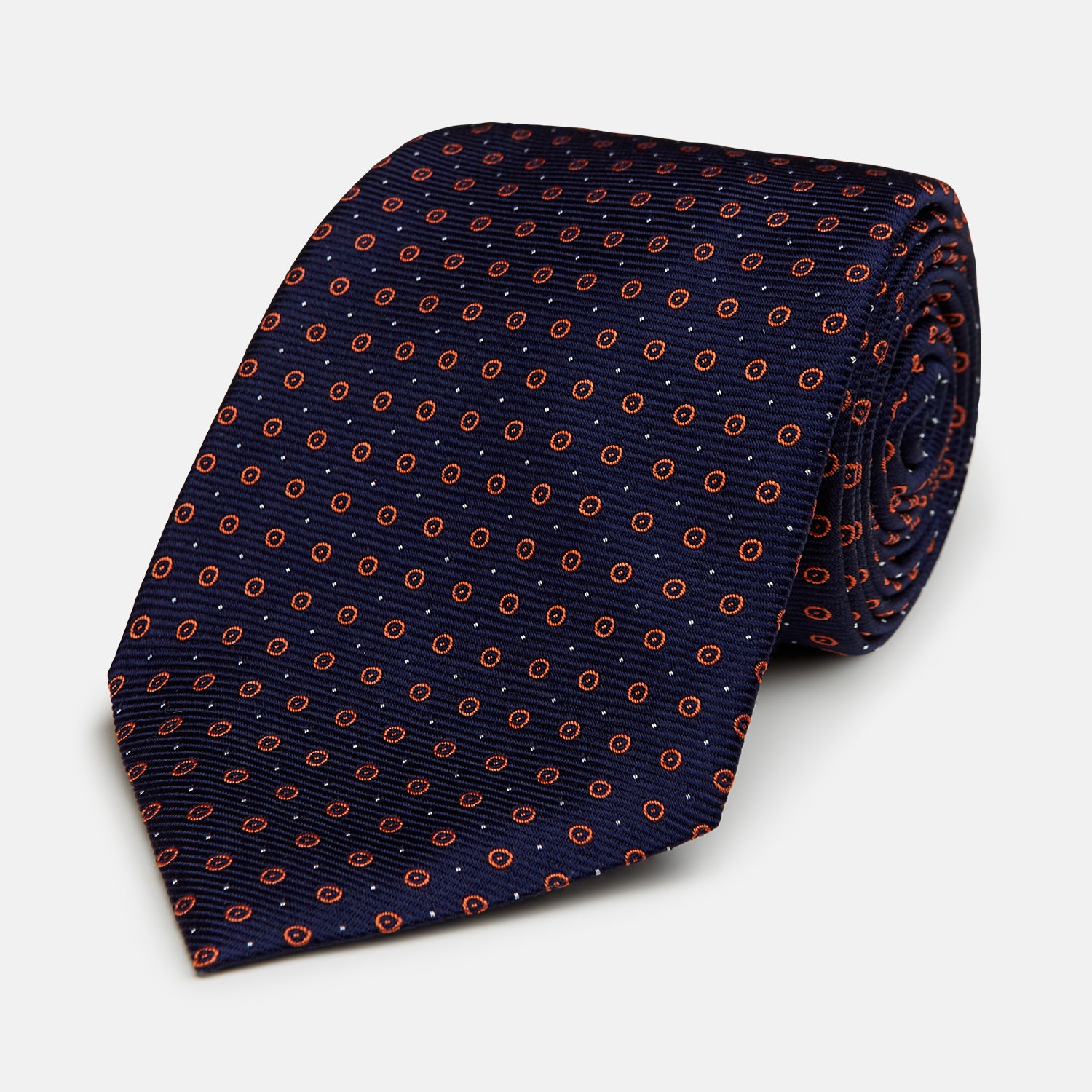 View 1 of product A Navy and Orange Circle Silk Tie by Turnbull & Asser, neatly rolled on a white background.