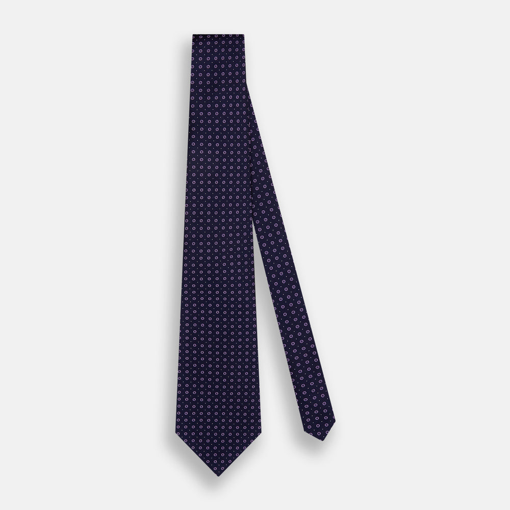 The Navy and Lilac Circle Silk Tie by Turnbull & Asser features pink and purple circles on dark navy silk, shown rolled on a white background—ideal for formal occasions.