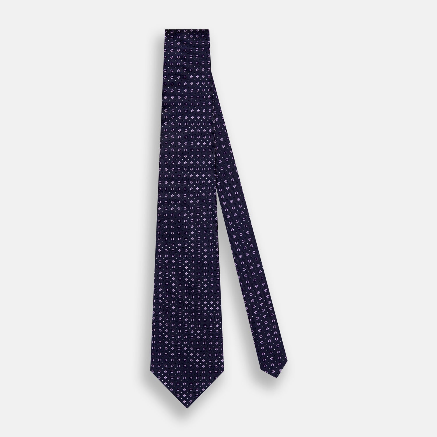 View 2 of product The Navy and Lilac Circle Silk Tie by Turnbull & Asser features pink and purple circles on dark navy silk, shown rolled on a white background—ideal for formal occasions.