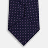 View 3 of product The Navy and Lilac Circle Silk Tie by Turnbull & Asser features pink and purple circles on dark navy silk, shown rolled on a white background—ideal for formal occasions.