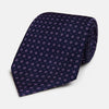 View 1 of product The Navy and Lilac Circle Silk Tie by Turnbull & Asser features pink and purple circles on dark navy silk, shown rolled on a white background—ideal for formal occasions.