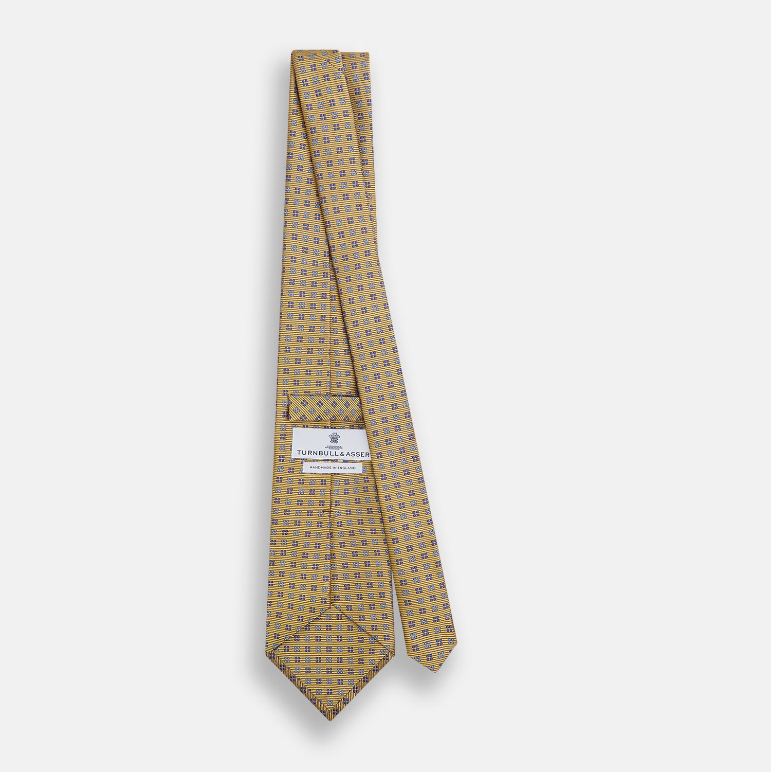 View 4 of product The Turnbull & Asser Blue and Gold Multi Dot Silk Tie features blue and gold dots in neat rows, presented rolled up on a white background.
