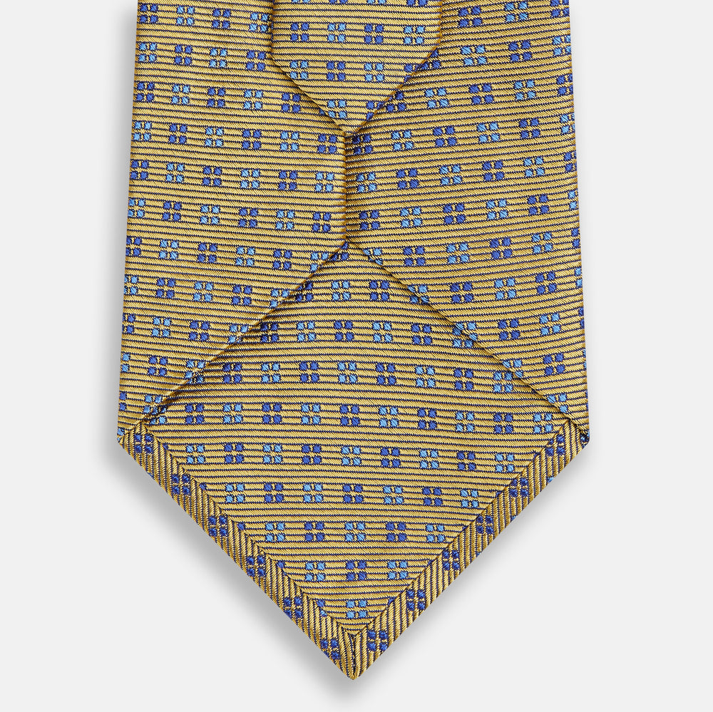 The Turnbull & Asser Blue and Gold Multi Dot Silk Tie features blue and gold dots in neat rows, presented rolled up on a white background.