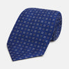 View 1 of product The Turnbull & Asser Blue and Brown Multi Dot Silk Tie, shown rolled up on a plain white background, features an elegant design with small white and gray dots arranged in squares.