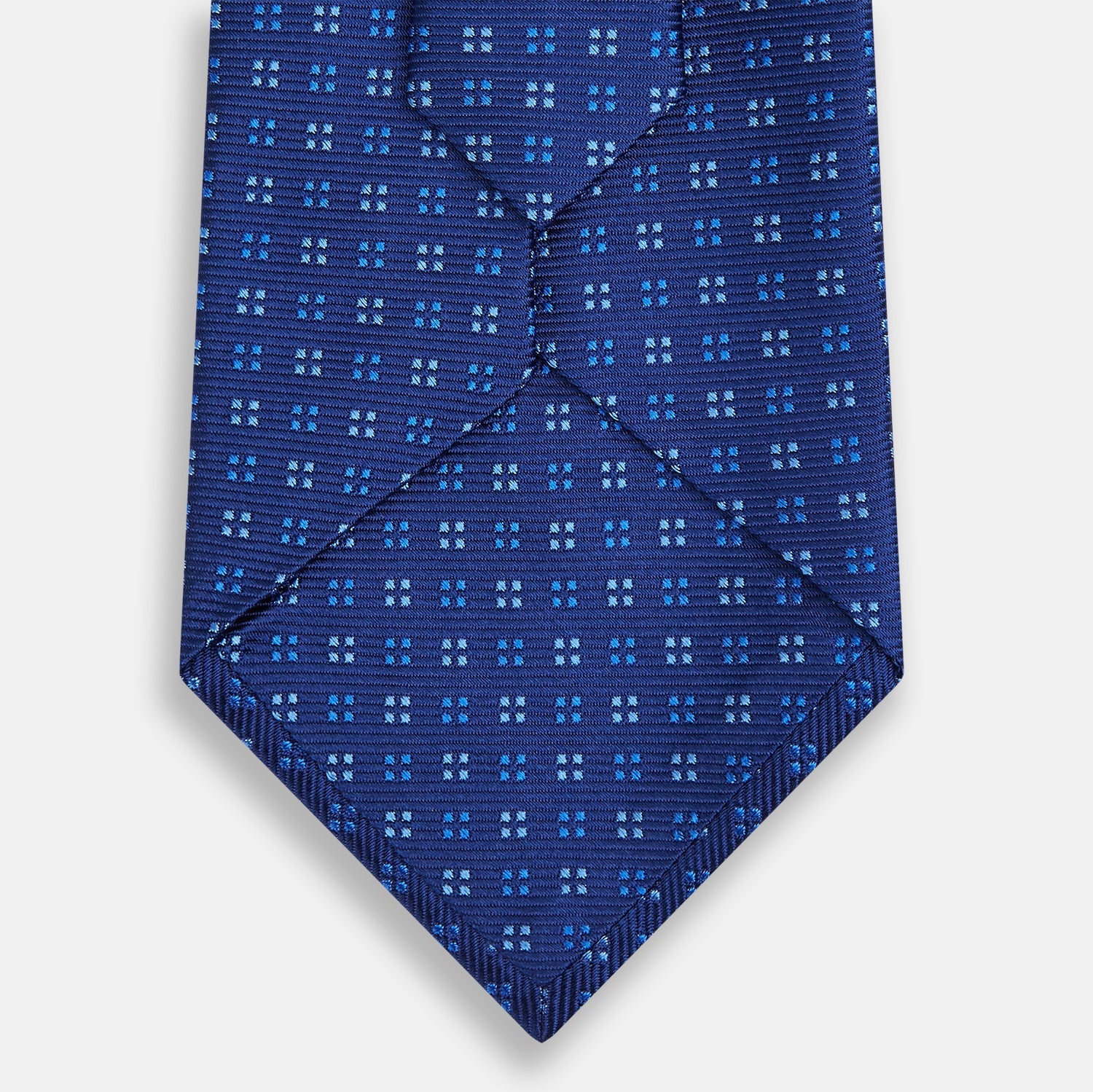 View 3 of product The Turnbull & Asser Blue Multi Dot Silk Tie features a rolled-up blue design with small light blue dots, offering an elegant, refined accent to office attire.
