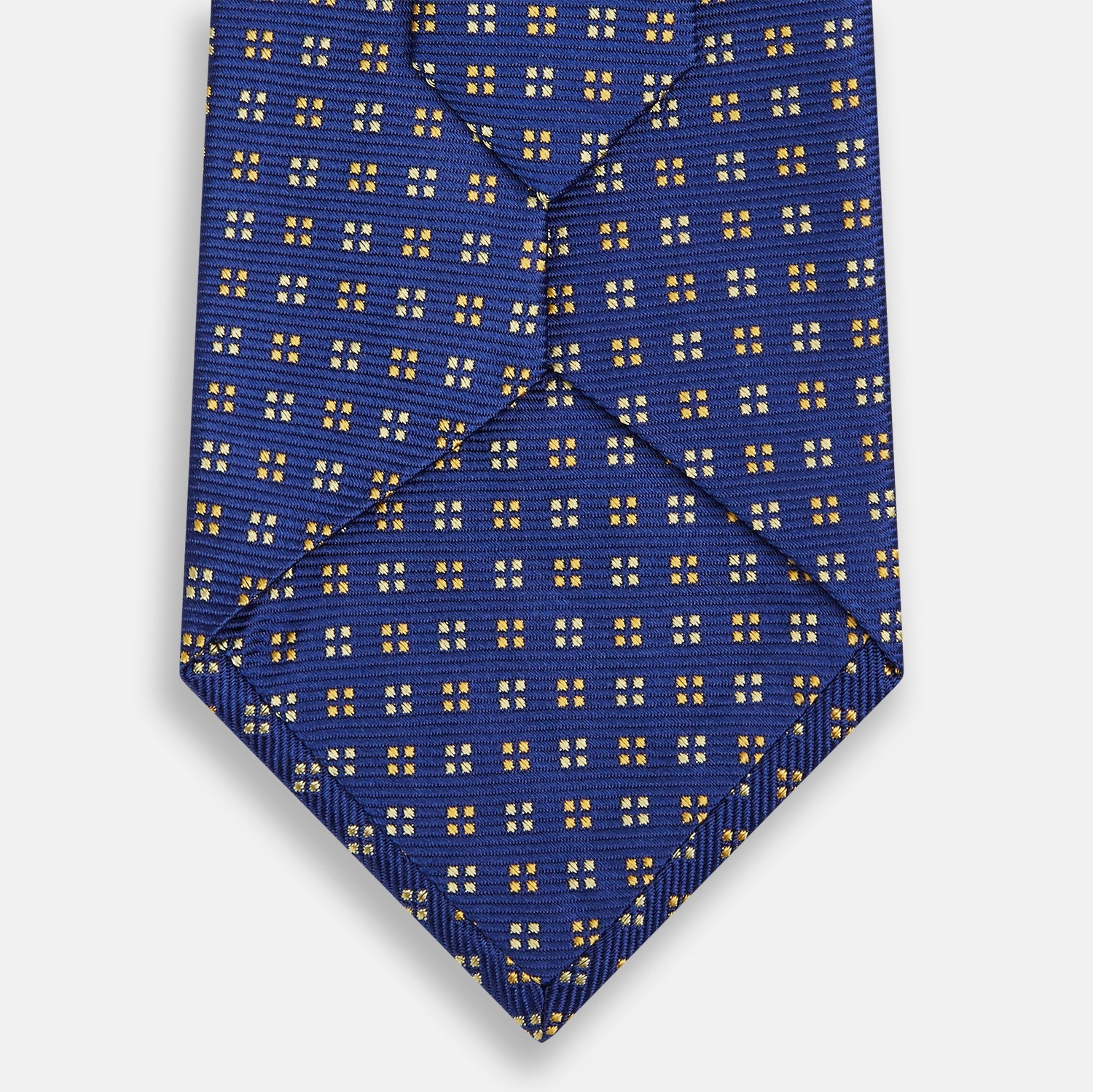 View 3 of product The Turnbull & Asser Blue and Yellow Multi Dot Silk Tie features a geometric yellow and white pattern, ideal for modern office wear. The elegant silk tie is showcased rolled up on a plain white background.