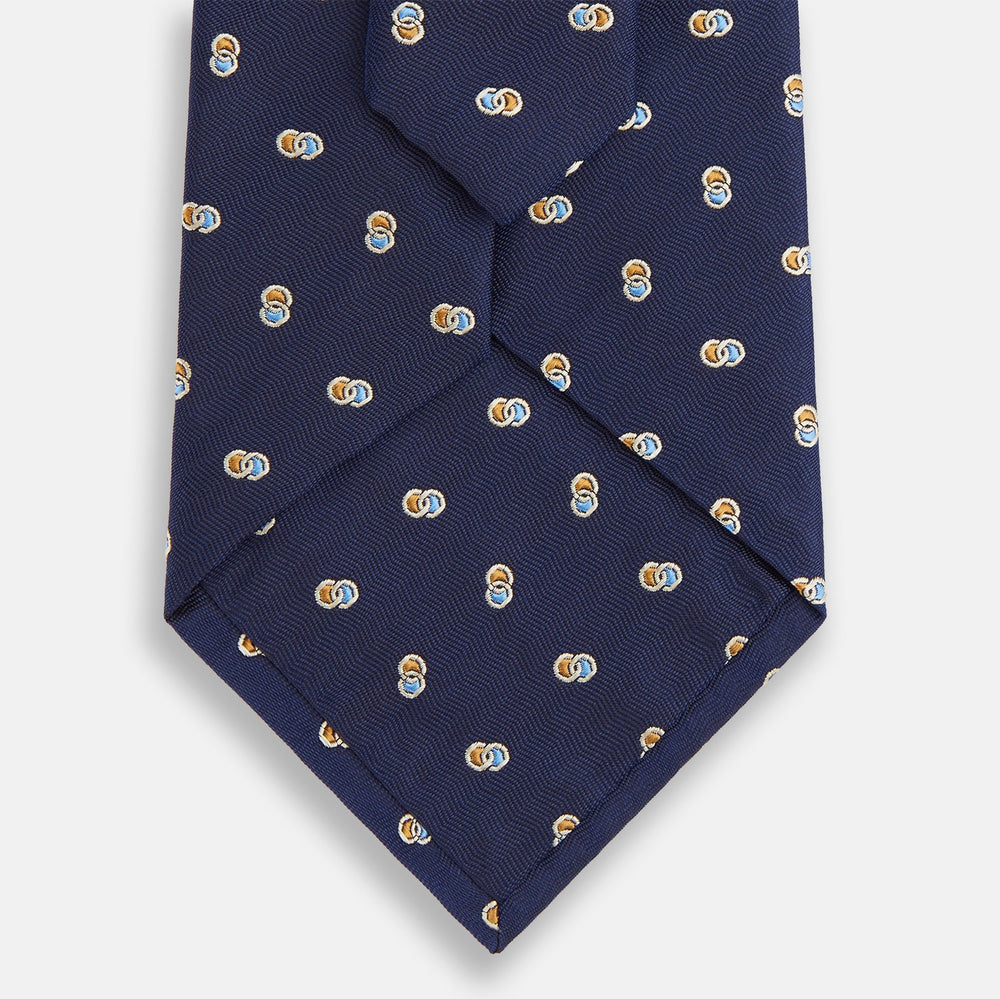 The Turnbull & Asser Blue and Yellow Links Silk Tie features a refined zigzag texture and a repeating pattern of interlocking gold and blue rings—the perfect sophisticated accent for the modern gentleman, especially paired with Turnbull & Asser shirts.