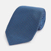 View 1 of product The Turnbull & Asser Blue Geometric Silk Tie features a textured woven pattern with lighter blue accents, shown neatly rolled on a plain white background.