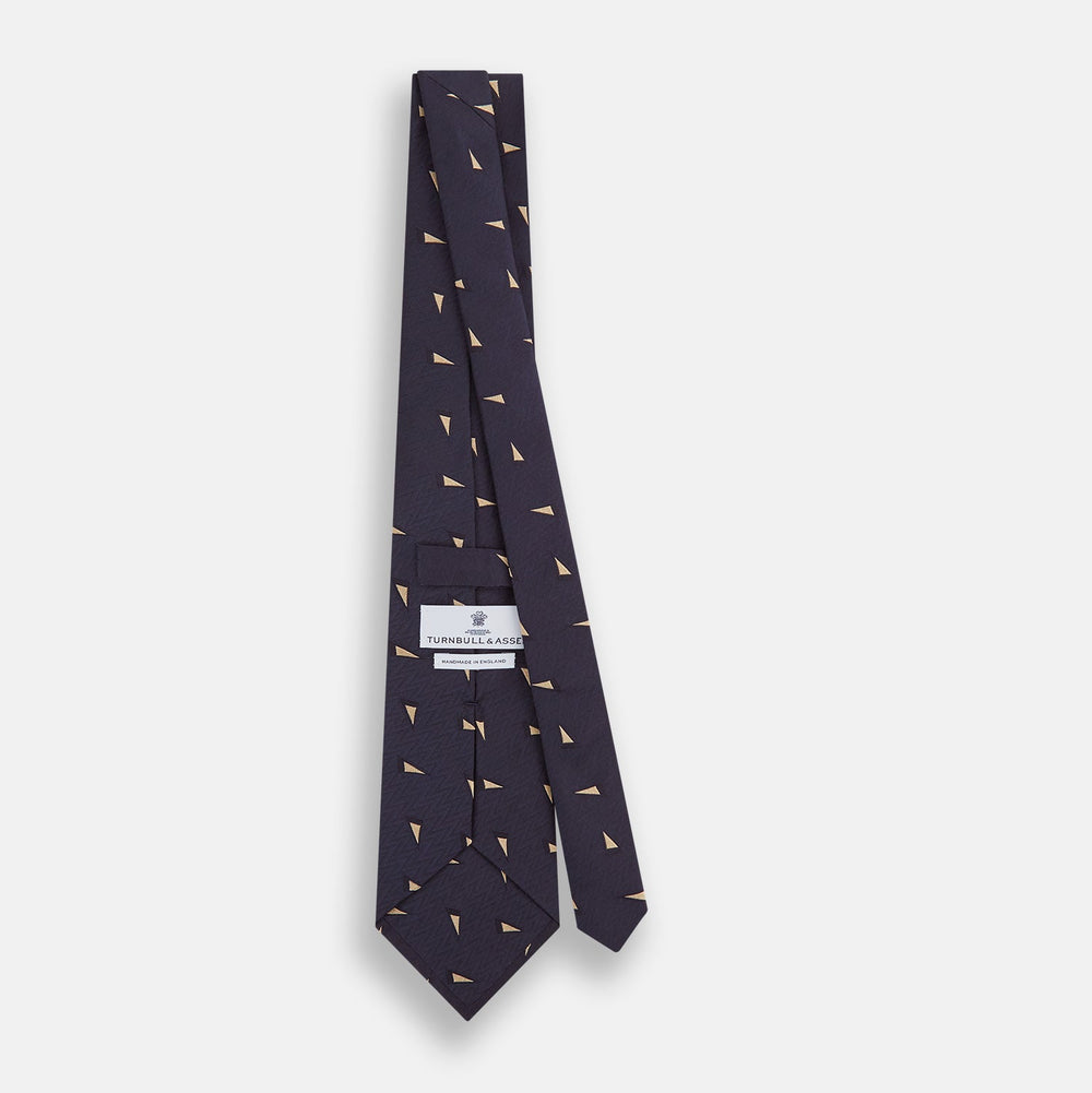 The Navy Triangle Silk Tie by Turnbull & Asser features an elegant gold micro triangle pattern on navy silk, making it a sophisticated accessory that pairs perfectly with Turnbull & Asser shirts.