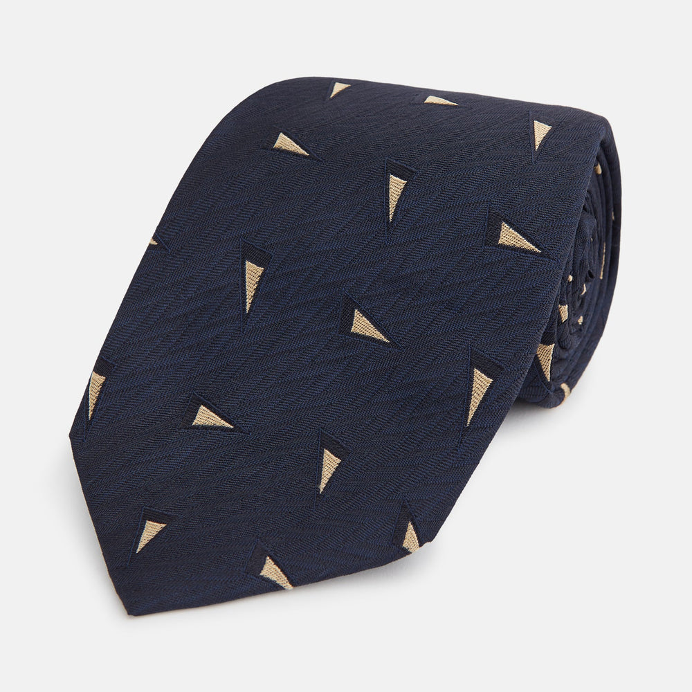 The Navy Triangle Silk Tie by Turnbull & Asser features an elegant gold micro triangle pattern on navy silk, making it a sophisticated accessory that pairs perfectly with Turnbull & Asser shirts.