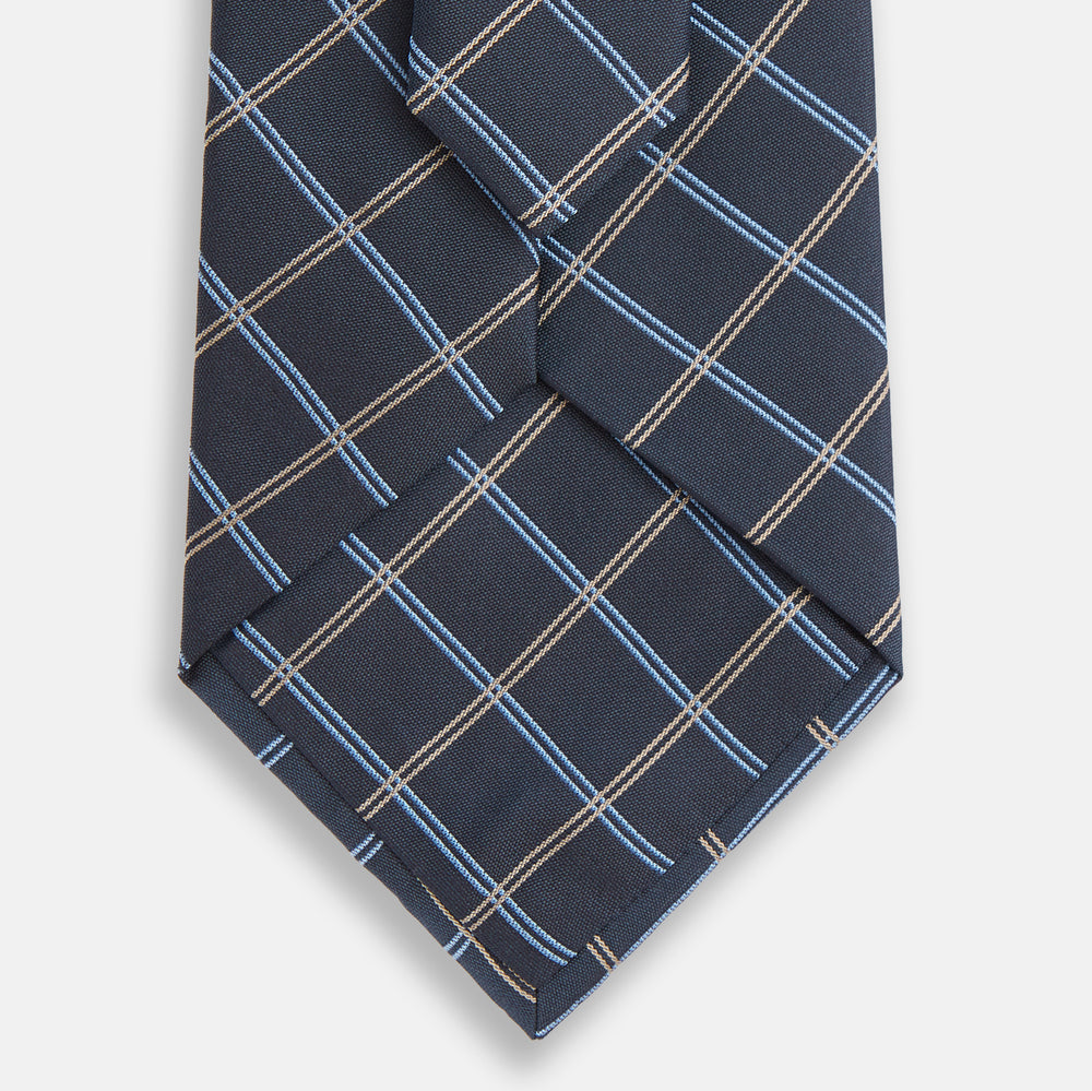 The Turnbull & Asser Navy Fine Double Check Silk Tie, featuring a refined navy, light blue, and tan plaid, is neatly rolled on a white background—an ideal accessory to complement any Turnbull & Asser shirt.