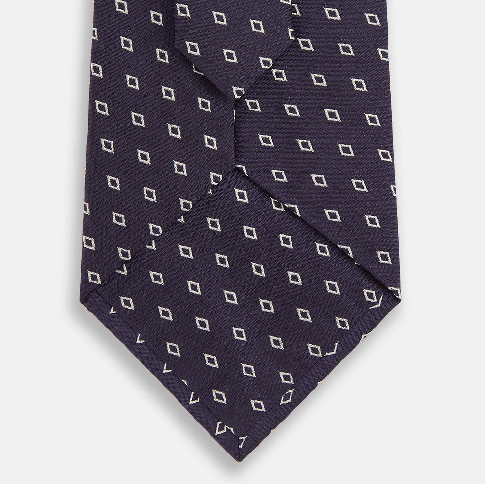 The Blue Diamond Silk Tie by Turnbull & Asser, featuring a blue micro diamond pattern, is rolled up and displayed on a white background. Perfect to complement Turnbull & Asser shirts.