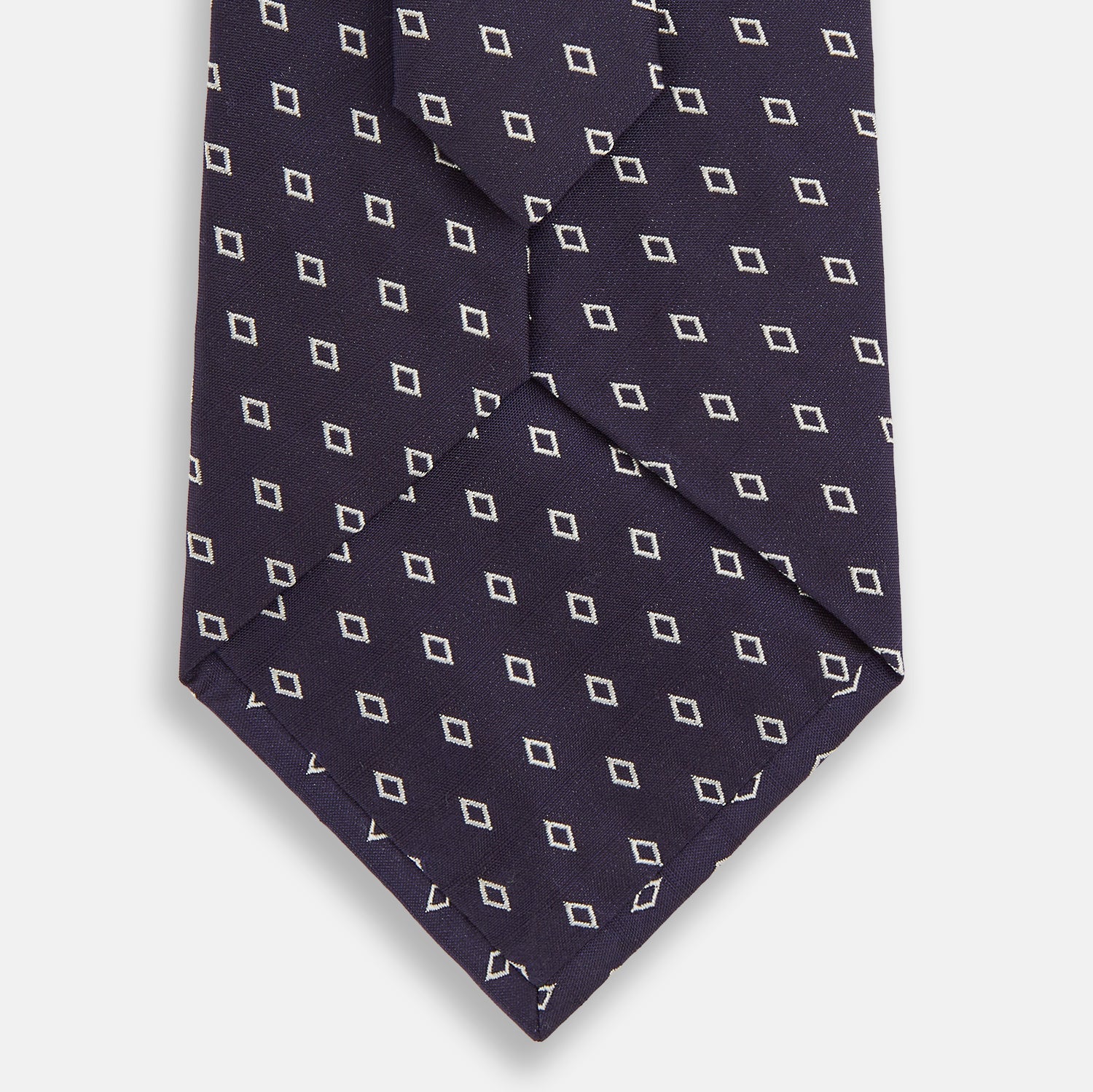 View 3 of product The Blue Diamond Silk Tie by Turnbull & Asser, featuring a blue micro diamond pattern, is rolled up and displayed on a white background. Perfect to complement Turnbull & Asser shirts.