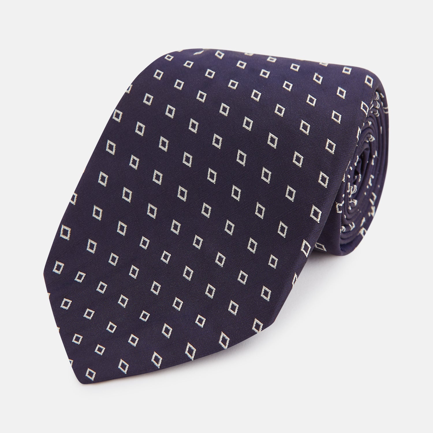 View 1 of product The Blue Diamond Silk Tie by Turnbull & Asser, featuring a blue micro diamond pattern, is rolled up and displayed on a white background. Perfect to complement Turnbull & Asser shirts.