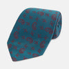 View 1 of product The Teal Paisley Silk Tie by Turnbull & Asser features a red paisley and small floral pattern, shown rolled with the pointed end forward on a white background.