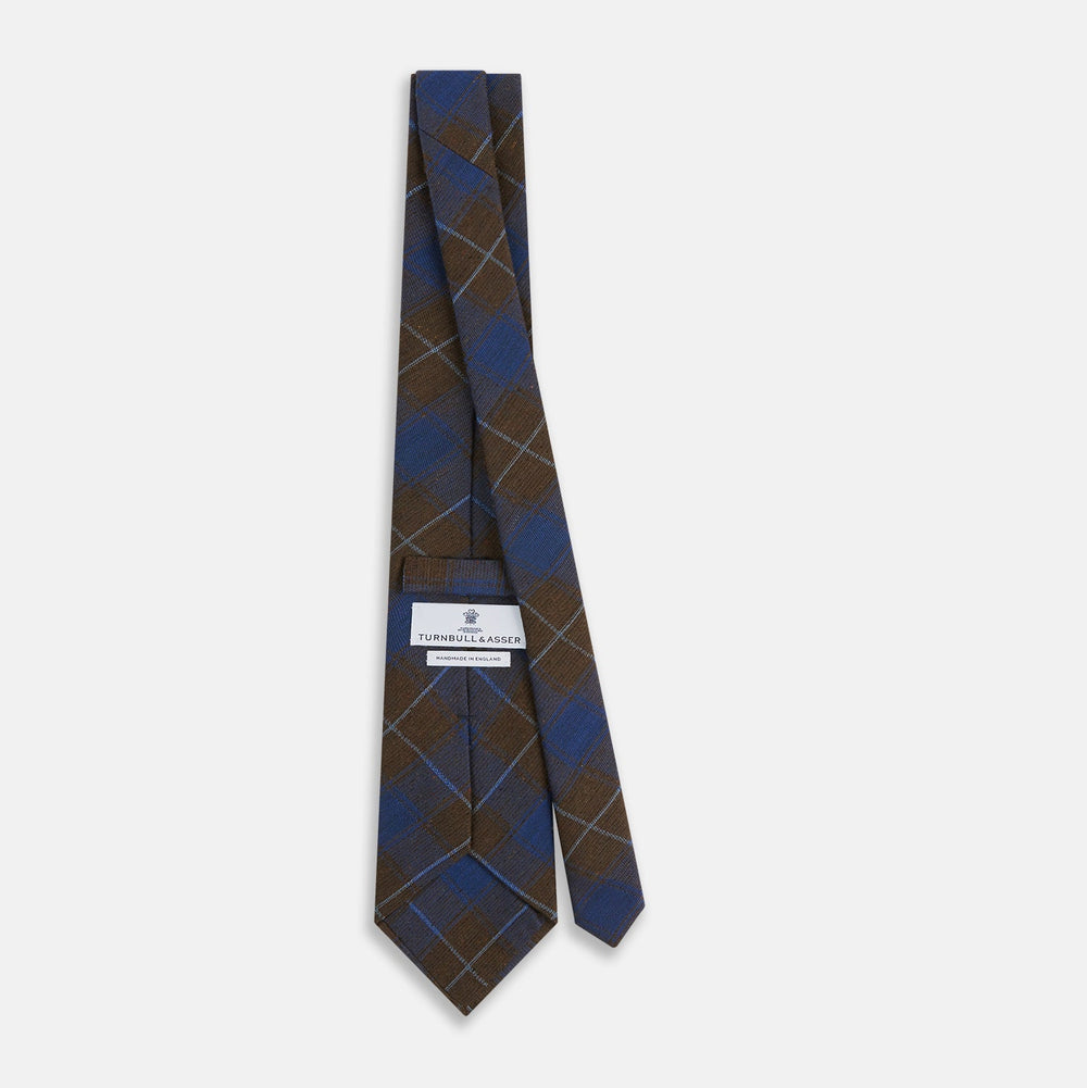 The Turnbull & Asser Blue and Brown Tartan Silk Blend Tie, rolled up to show intersecting patterns, is displayed against a plain white background.