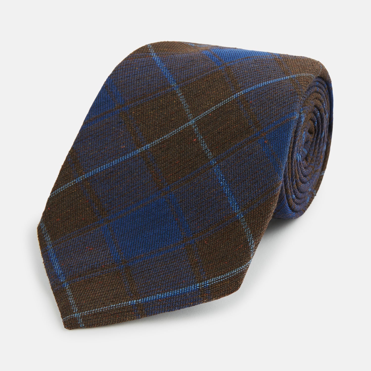 View 1 of product The Turnbull & Asser Blue and Brown Tartan Silk Blend Tie, rolled up to show intersecting patterns, is displayed against a plain white background.