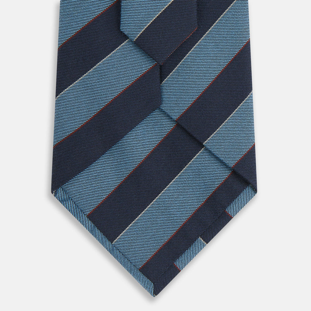 The Blue Block Stripe Silk Blend Tie by Turnbull & Asser features light blue and navy diagonal stripes with thin red lines—a stylish accessory that pairs perfectly with Turnbull & Asser shirts. Displayed rolled-up on a white background.