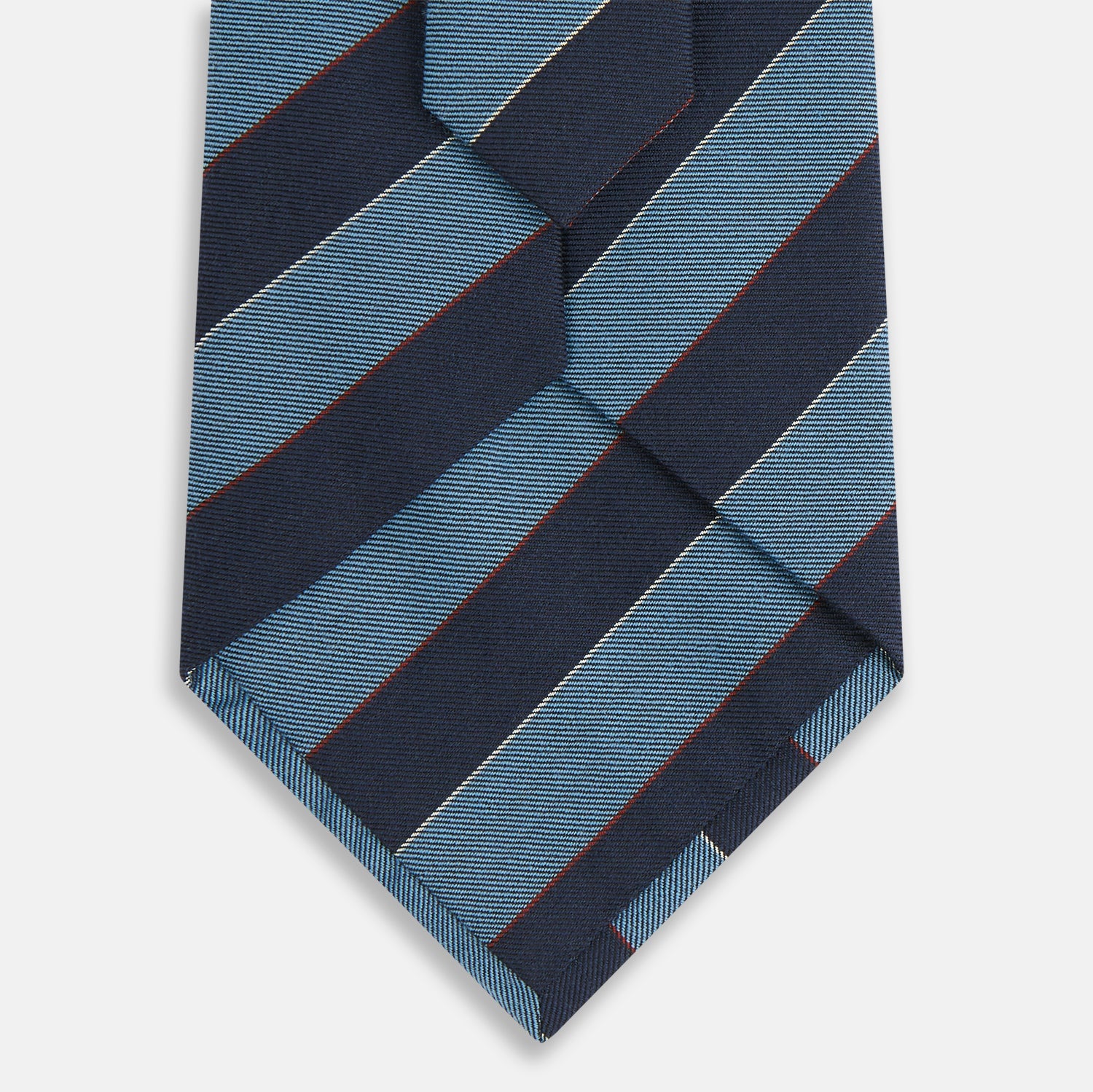 View 3 of product The Blue Block Stripe Silk Blend Tie by Turnbull & Asser features light blue and navy diagonal stripes with thin red lines—a stylish accessory that pairs perfectly with Turnbull & Asser shirts. Displayed rolled-up on a white background.