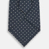 View 3 of product The Turnbull & Asser Navy Micro Dot Silk Tie features a handmade navy blue silk fabric with evenly spaced small white dots, rolled up on a plain white background—a timeless formal accessory for any event.