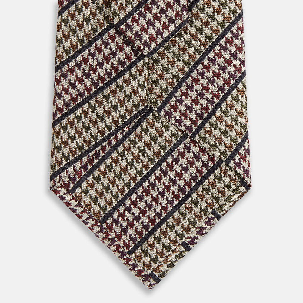 The Turnbull & Asser Brown Puppytooth Stripe Silk Tie features a brown, burgundy, and cream houndstooth pattern with black and white diagonal stripes—ideal for pairing with Turnbull & Asser shirts.