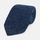 The Turnbull & Asser Navy Floret Silk Tie features a rolled-up deep blue silk fabric with a textured finish and small teal dot details, shown against a white background.