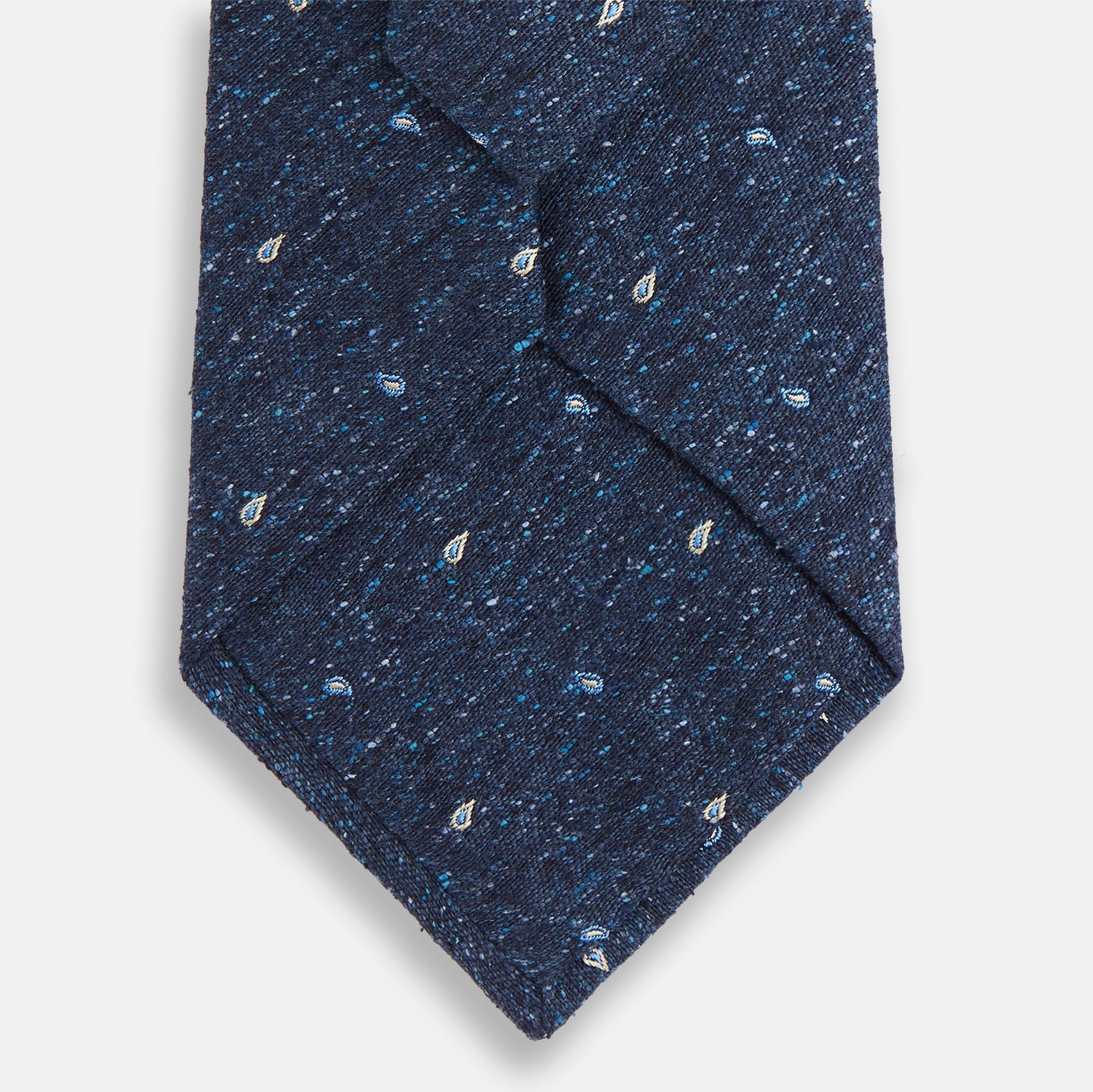 View 3 of product The Turnbull & Asser Navy Micro Paisley Silk Tie features a rolled-up navy blue silk with a subtle speckled texture and small light blue paisley patterns, perfect for enhancing any formal collection, shown on a white background.