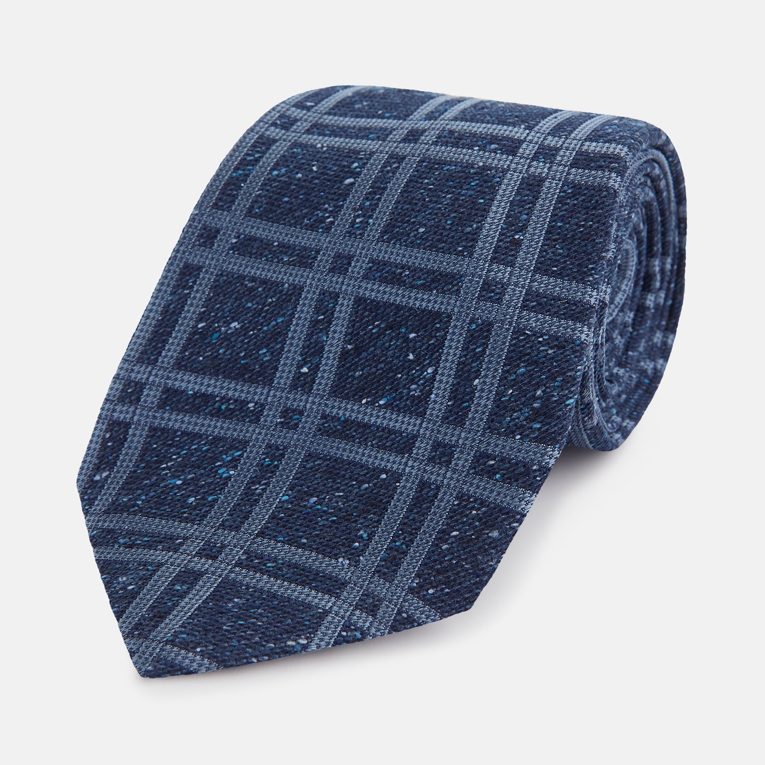 View 1 of product The Turnbull & Asser Navy Bold Double Check Silk Tie features a textured navy fabric with a light blue windowpane plaid pattern. This handmade silk tie is neatly rolled on a white background.