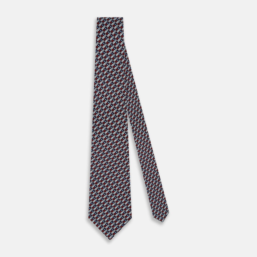 The Turnbull & Asser UK TIES 9.5CM GEOMETRIC RECTANGLES RED is an English silk tie with small red, navy blue, and white rectangles and dots on a white background.