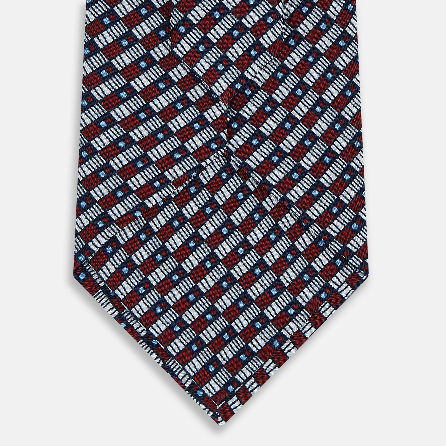 View 3 of product The Turnbull & Asser UK TIES 9.5CM GEOMETRIC RECTANGLES RED is an English silk tie with small red, navy blue, and white rectangles and dots on a white background.