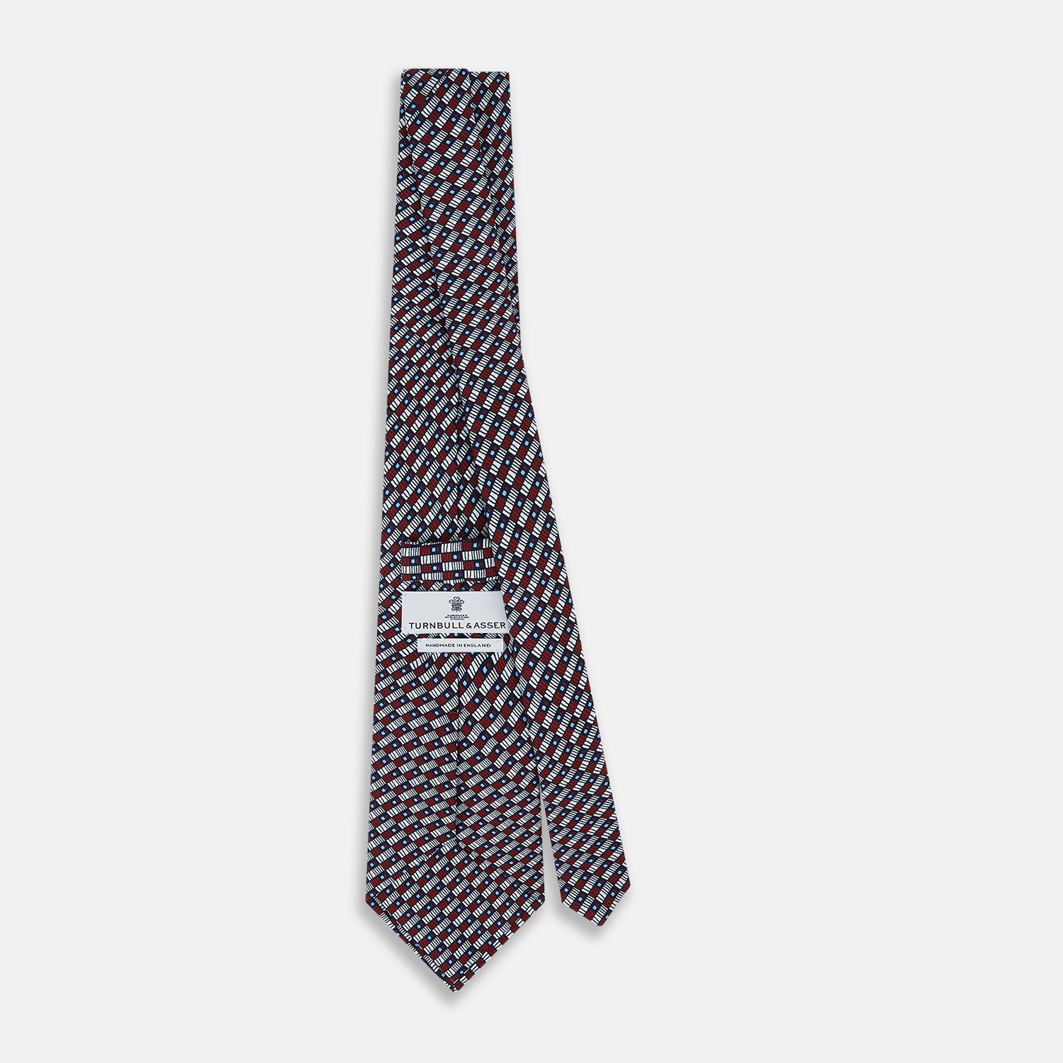 View 4 of product The Turnbull & Asser UK TIES 9.5CM GEOMETRIC RECTANGLES RED is an English silk tie with small red, navy blue, and white rectangles and dots on a white background.