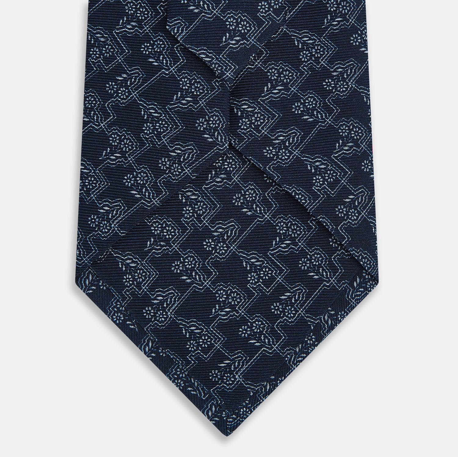 View 3 of product The Turnbull & Asser UK Midnight Blue Floral Jigsaw Printed Silk Tie features a light blue geometric and floral pattern on premium English silk, with a pointed tip and textured finish for an elegant touch.