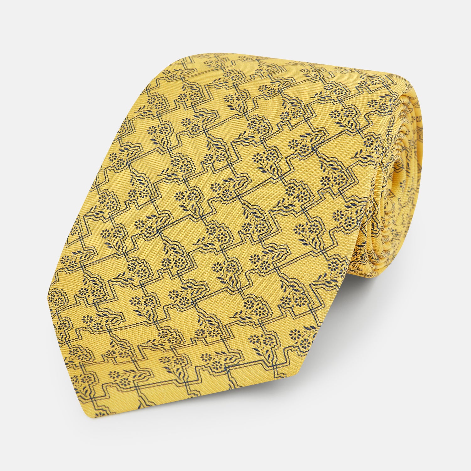 View 1 of product The Turnbull & Asser UK Yellow Floral Jigsaw Printed Silk Tie is neatly rolled to showcase its vibrant yellow hue and intricate floral jigsaw print.