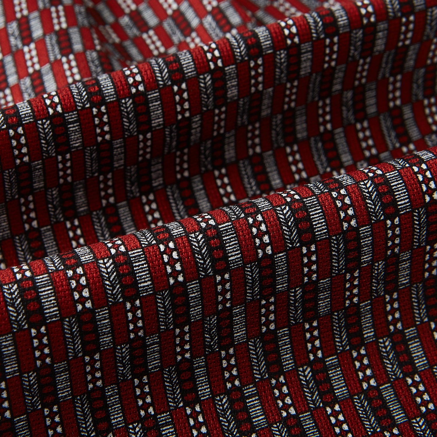 View 4 of product Close-up of the Red Hatched Mosaic Printed Silk Cravat by Turnbull & Asser UK, featuring black and white geometric shapes, parallel lines, and a textured finish in a classic British style.
