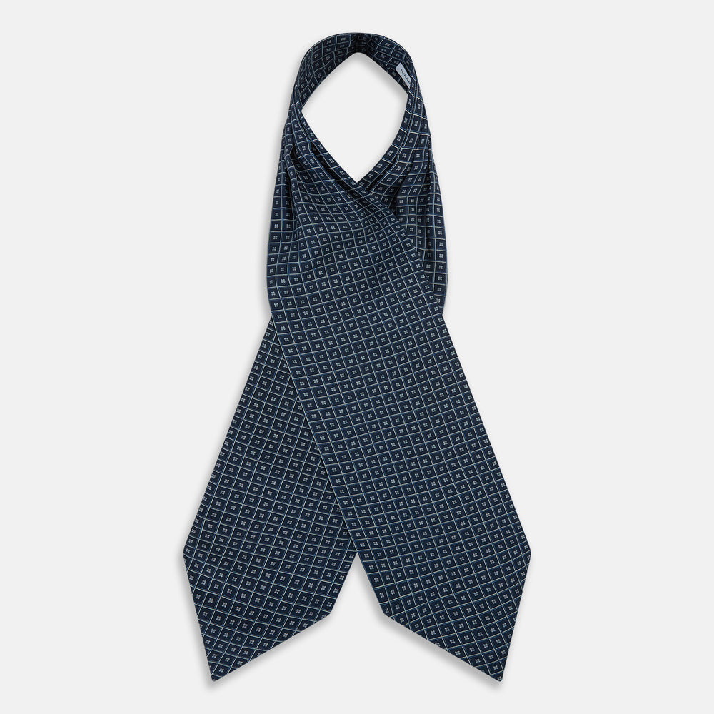 A folded Geometric Navy Quatrefoil Motif Ascot Tie in Silk, featuring a navy ground with a white grid pattern and small quatrefoil motifs in each square.