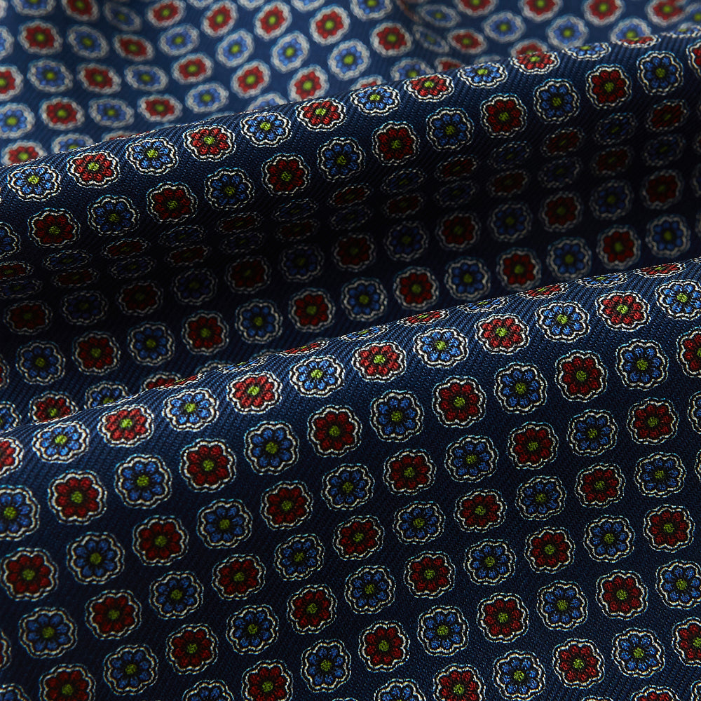 The Turnbull & Asser UK Midnight Blue Contrasting Rosette Medallion Printed Silk Cravat features a grid of small red, yellow, and blue floral patterns on textured silk—evoking classic British style.