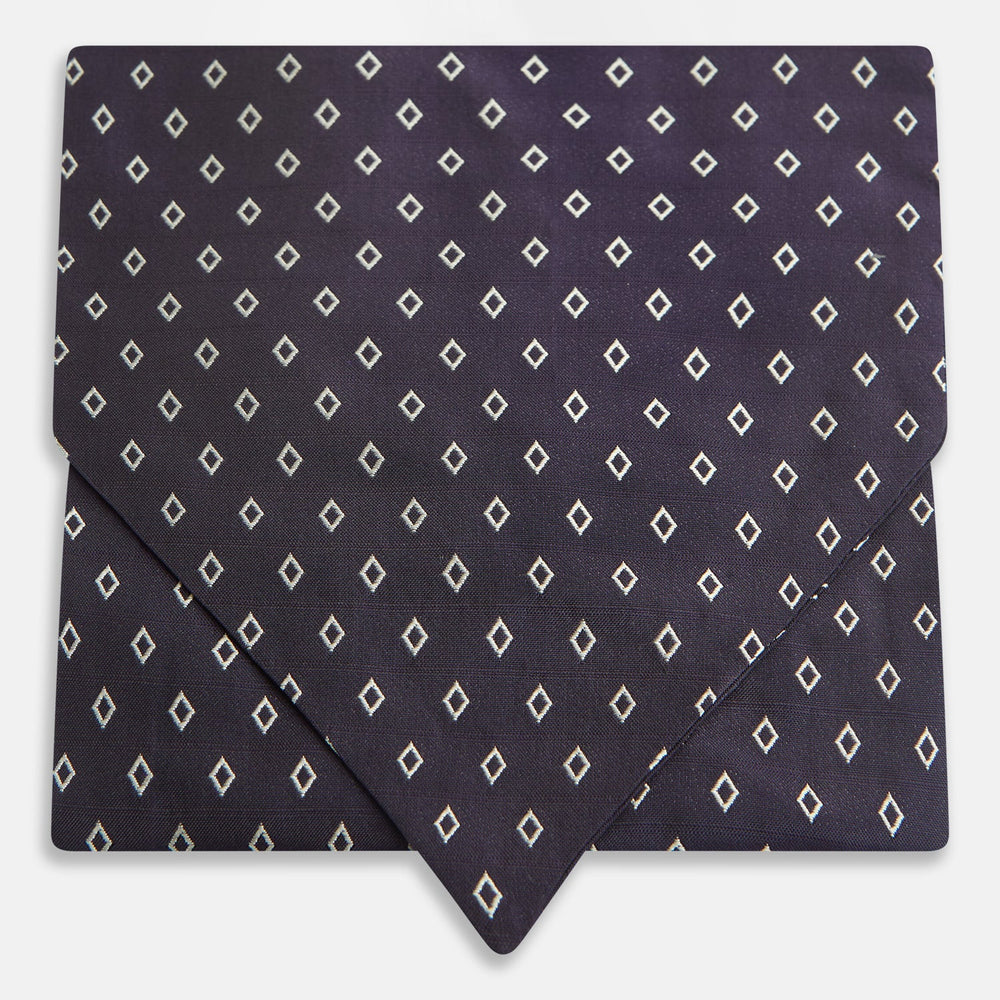 The Turnbull & Asser Blue Diamond Silk Cravat is a refined men's formal accessory, featuring a navy blue base with small white diamond patterns—perfectly complemented by a neatly folded, pointed-corner pocket square.