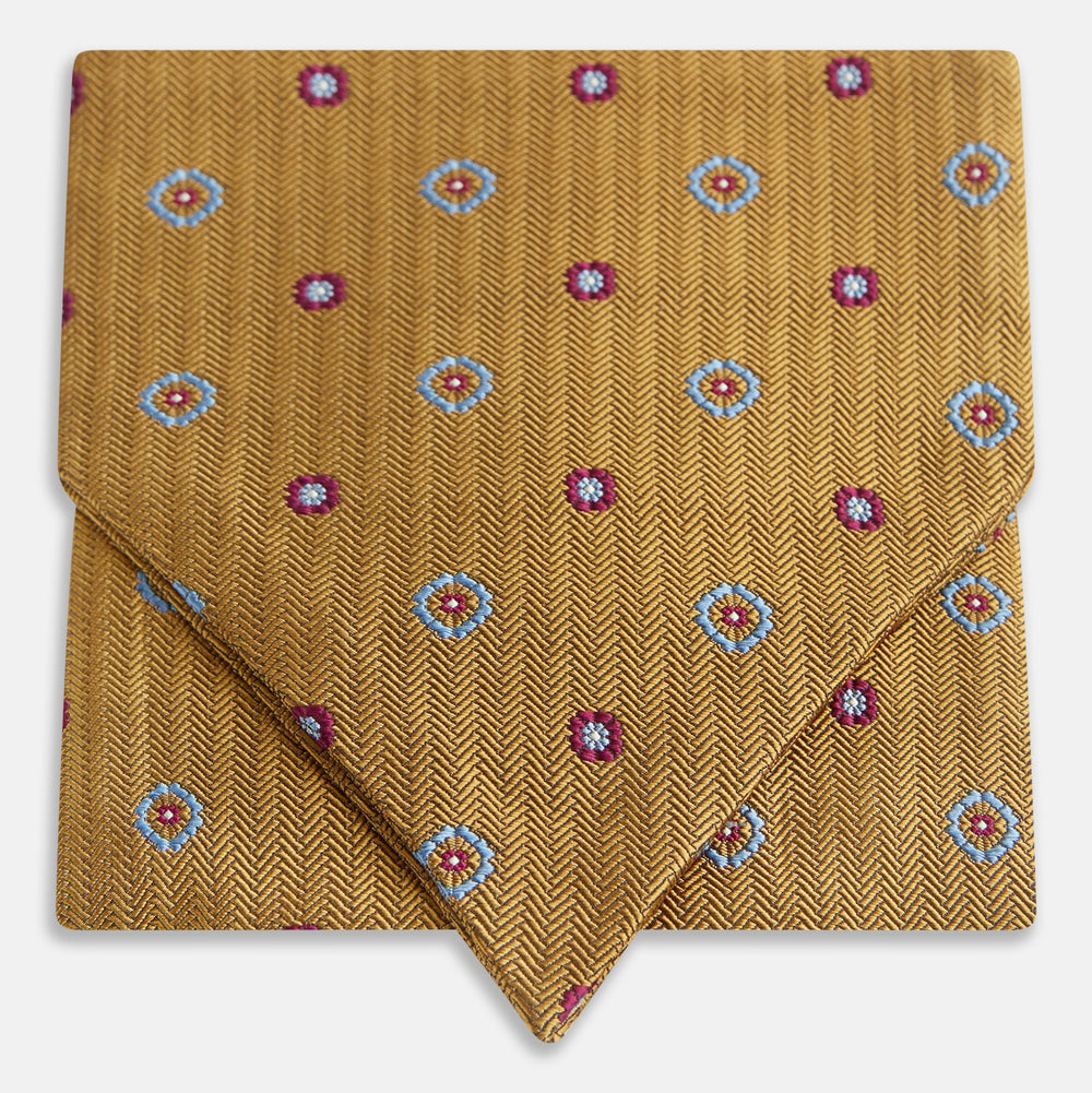The Turnbull & Asser Gold Motif Silk Cravat features a herringbone pattern with blue and red floral accents—stylishly folded with a pointed tip, it's ideal for elevating your look at formal events.