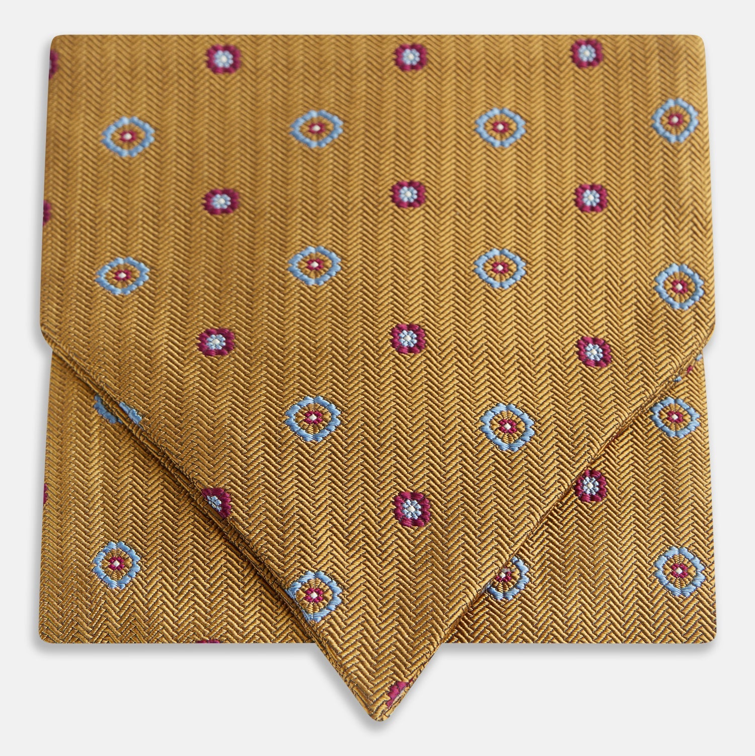 View 1 of product The Turnbull & Asser Gold Motif Silk Cravat features a herringbone pattern with blue and red floral accents—stylishly folded with a pointed tip, it's ideal for elevating your look at formal events.