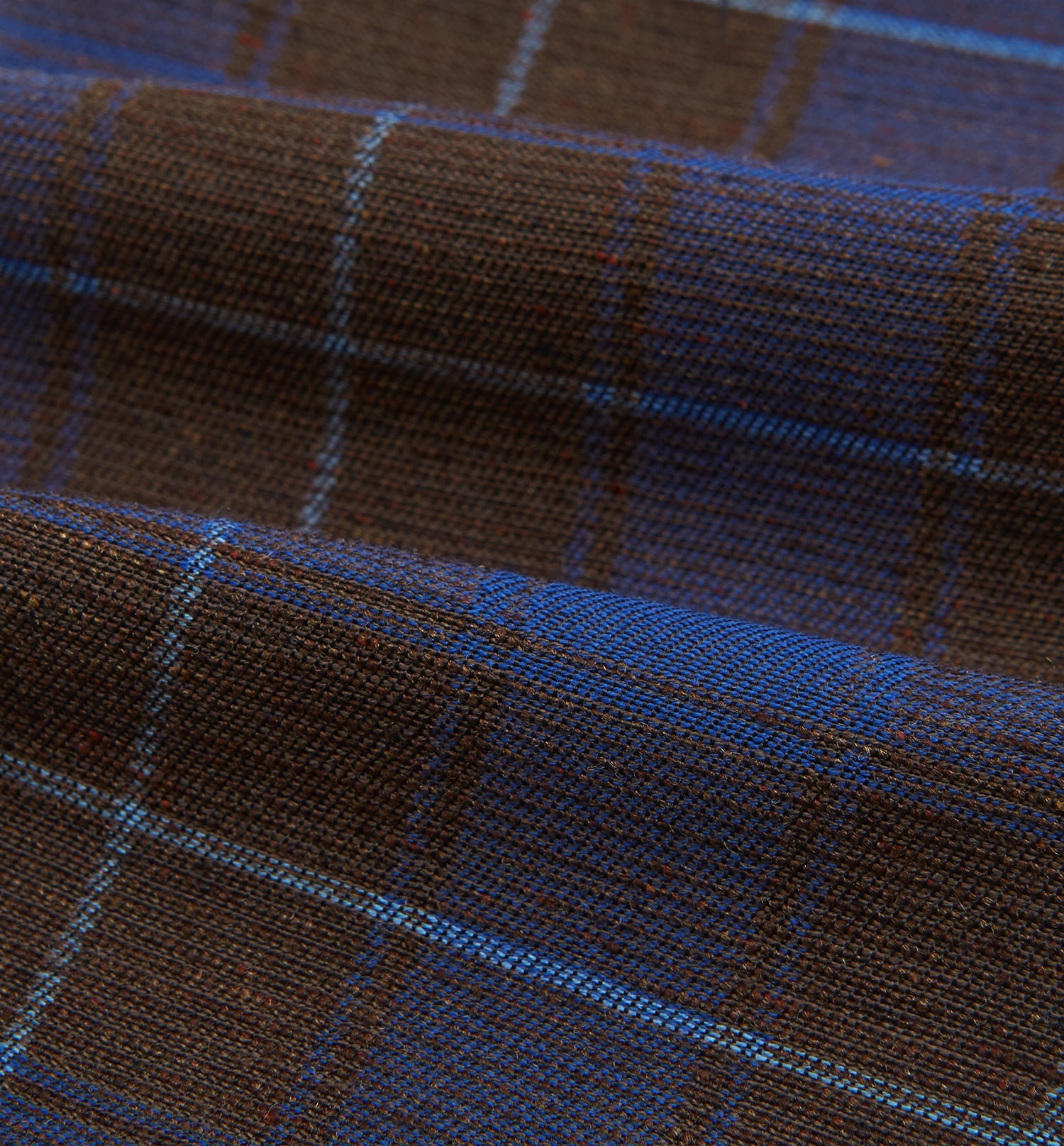 View 4 of product The Turnbull & Asser Blue and Brown Tartan Silk Blend Cravat is neatly folded with sharp creases and displayed on a white background.