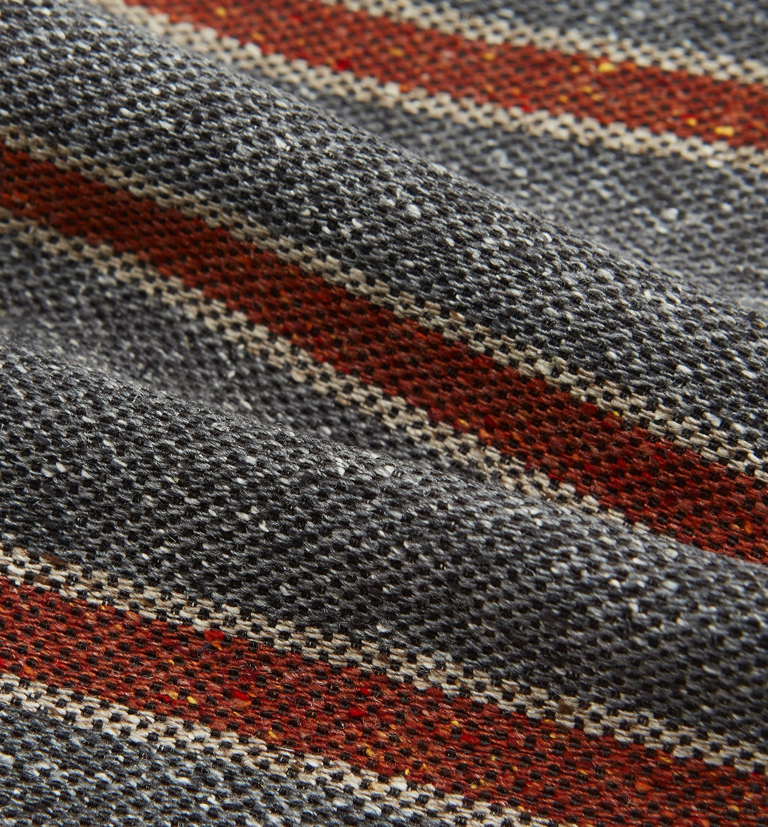 View 4 of product The Red Block Stripe Silk Cravat by Turnbull & Asser features gray textured fabric with two bold red-orange stripes and a pointed tip, reminiscent of handmade neckwear, shown against a white background.