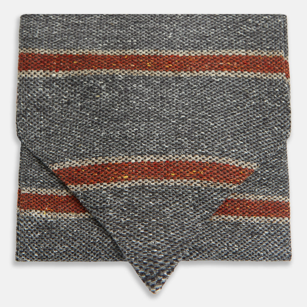 The Red Block Stripe Silk Cravat by Turnbull & Asser features gray textured fabric with two bold red-orange stripes and a pointed tip, reminiscent of handmade neckwear, shown against a white background.