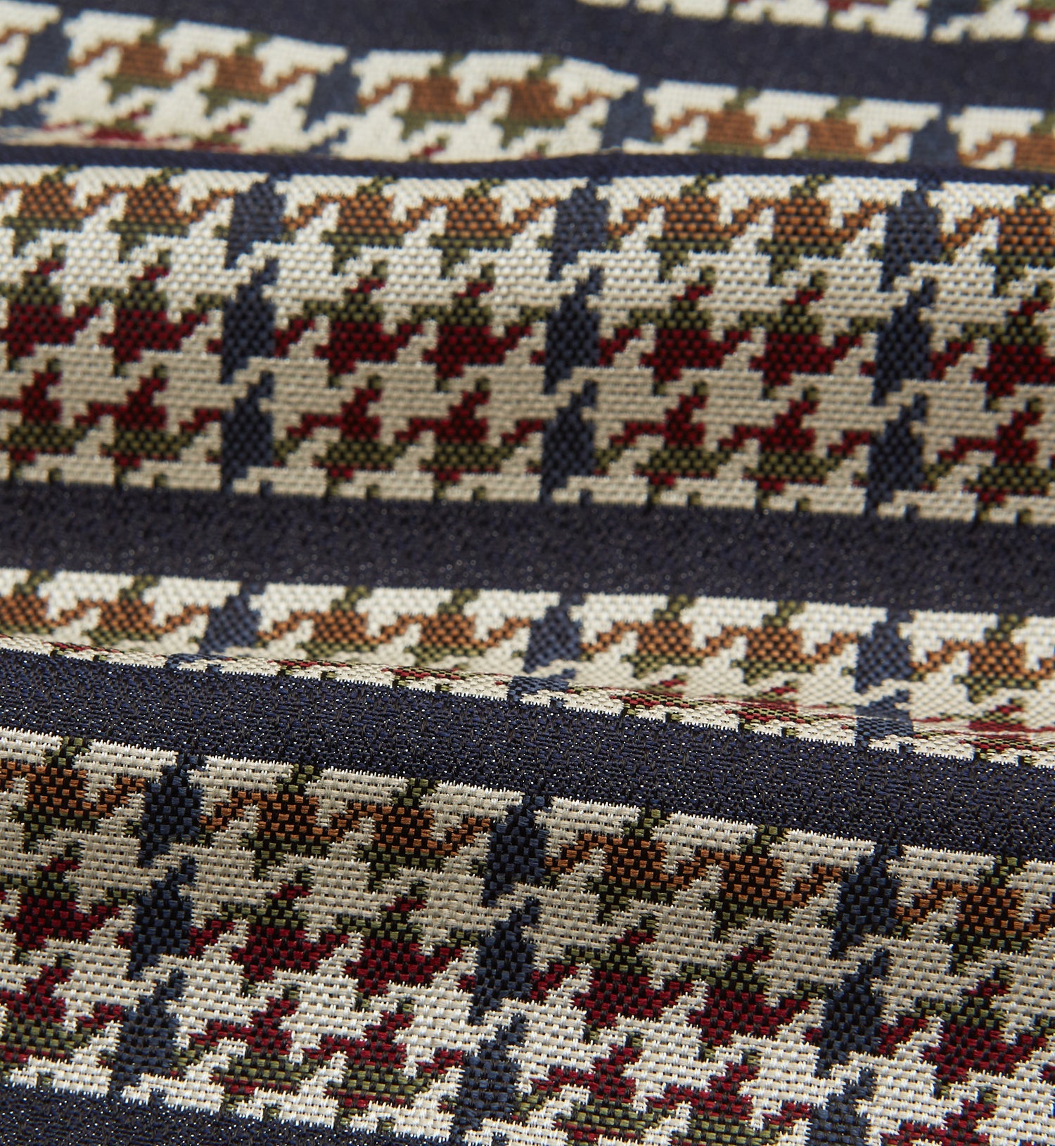 View 4 of product A folded pocket square with a houndstooth pattern in cream, brown, olive green, and burgundy with navy stripes—ideal for pairing with the Turnbull & Asser Brown Houndstooth Silk Cravat.