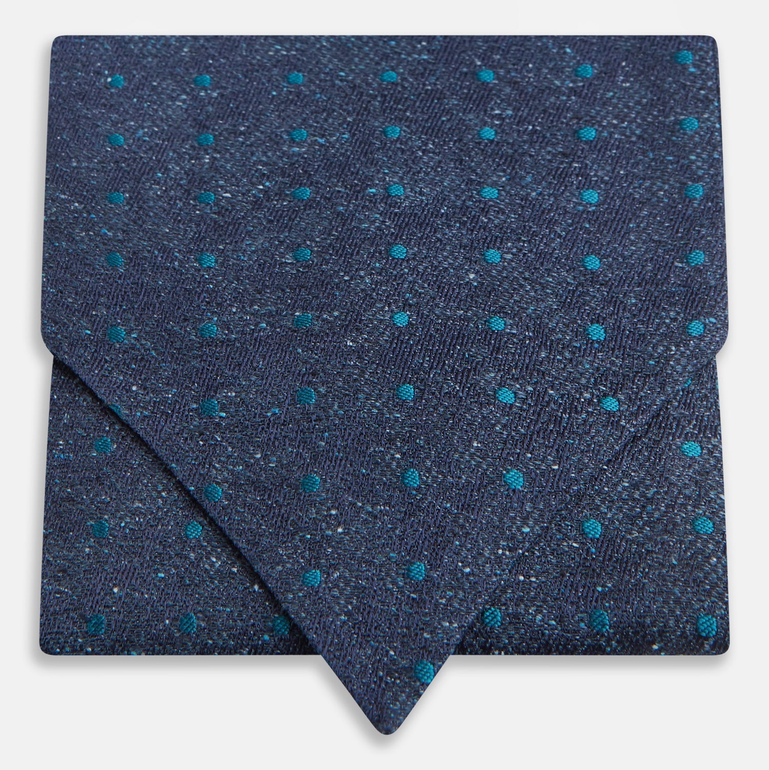 View 1 of product The Teal Micro Dot Silk Cravat by Turnbull & Asser is a formal accessory in textured dark blue silk, with small turquoise polka dots and a pointed edge at the bottom.
