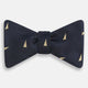 The Navy Triangle Silk Bow Tie by Turnbull & Asser features British elegance with a subtle herringbone pattern and scattered small gold triangle designs.