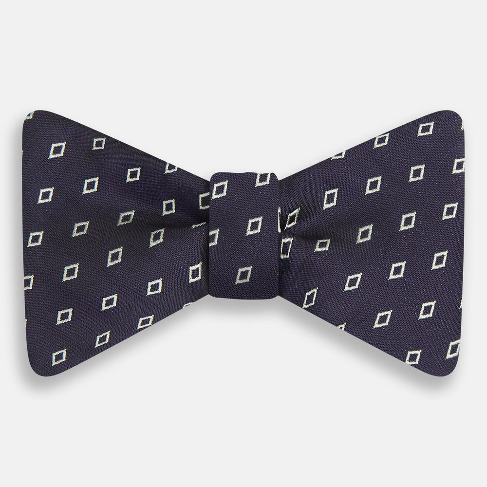 The Turnbull & Asser Blue Diamond Silk Bow Tie features small white diamond motifs on dark navy—perfect for adding classic British elegance to your formal look.