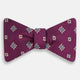 The Magenta Motif Silk Bow Tie by Turnbull & Asser features a textured magenta background with small, square blue, white, and gold geometric designs—an elegant choice for formal occasions.