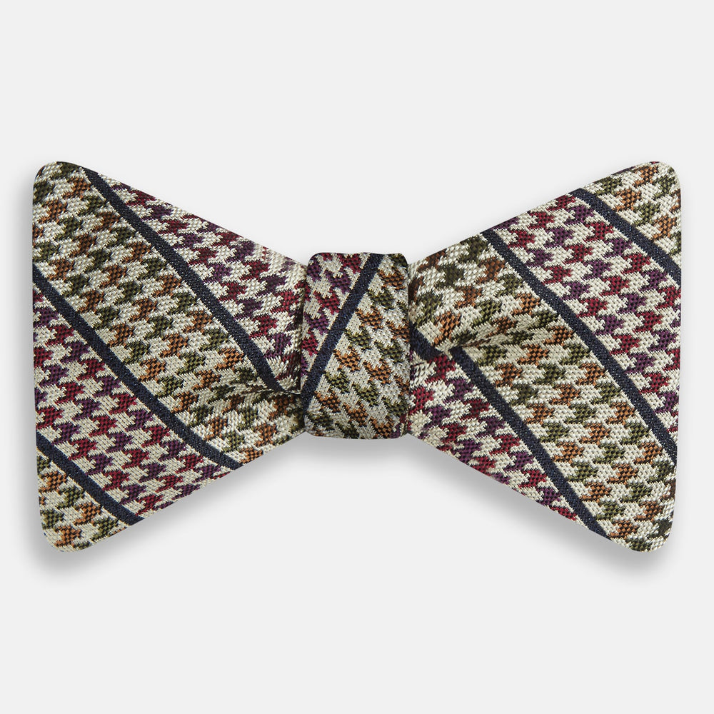 The Brown Puppytooth Stripe Silk Bow Tie by Turnbull & Asser features a houndstooth pattern in brown, beige, and burgundy with navy stripes—an elegant choice for formal occasions. Shown on a crisp white background.
