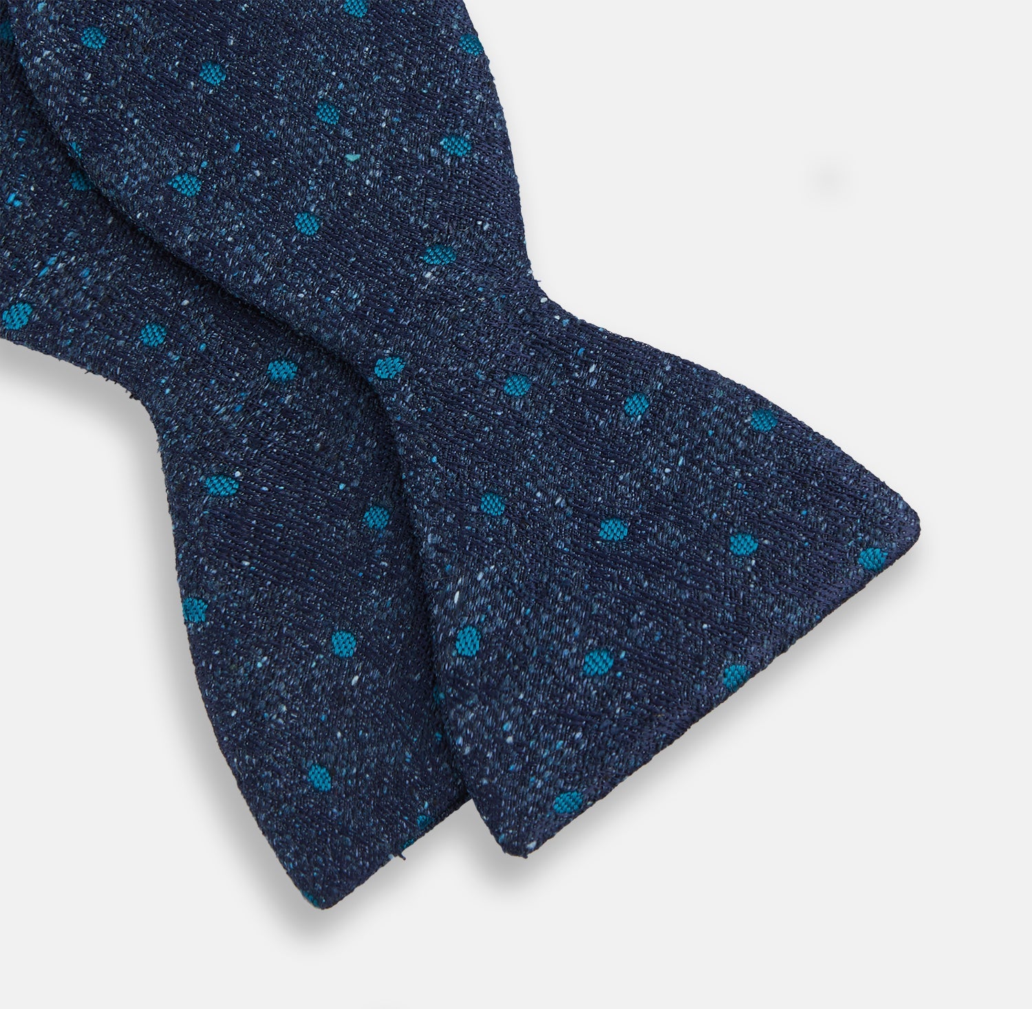 View 3 of product The Turnbull & Asser Teal Micro Dot Silk Bow Tie features textured navy blue silk with small teal dots, showcasing British elegance against a white background.